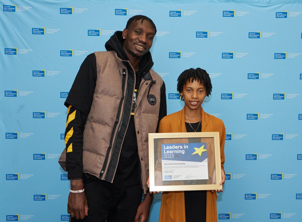 Chris Boucher stands with Helen Harry, who is holding a framed certificate.