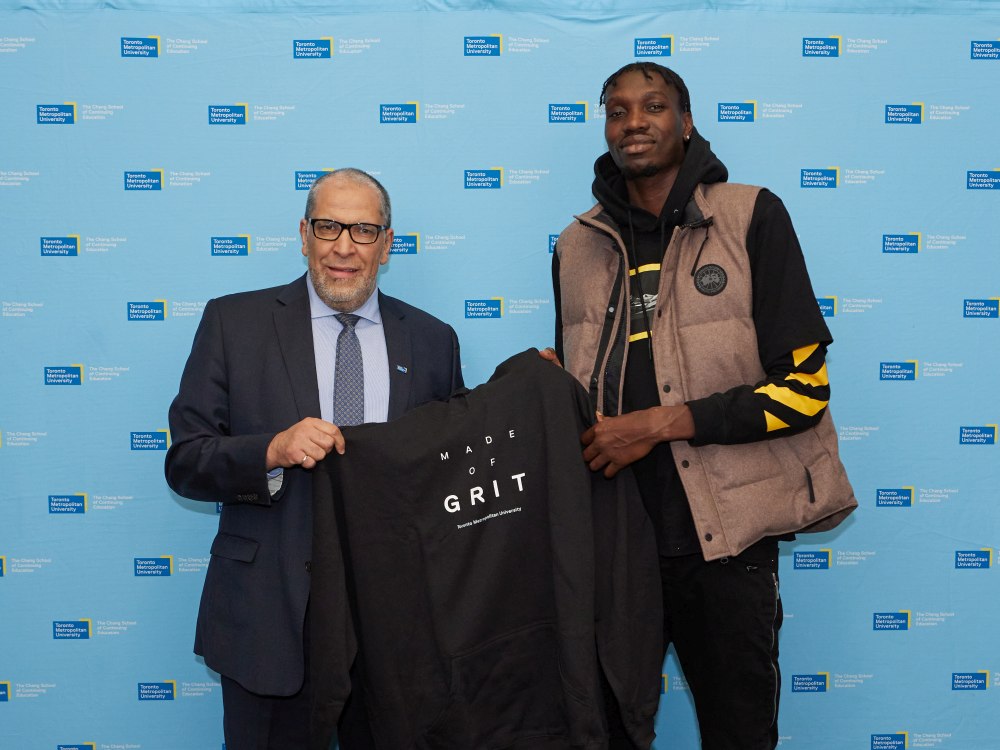 Mohamed Lachemi and Chris Boucher holding a hoodie with ‘Made of Grit’ written on it.