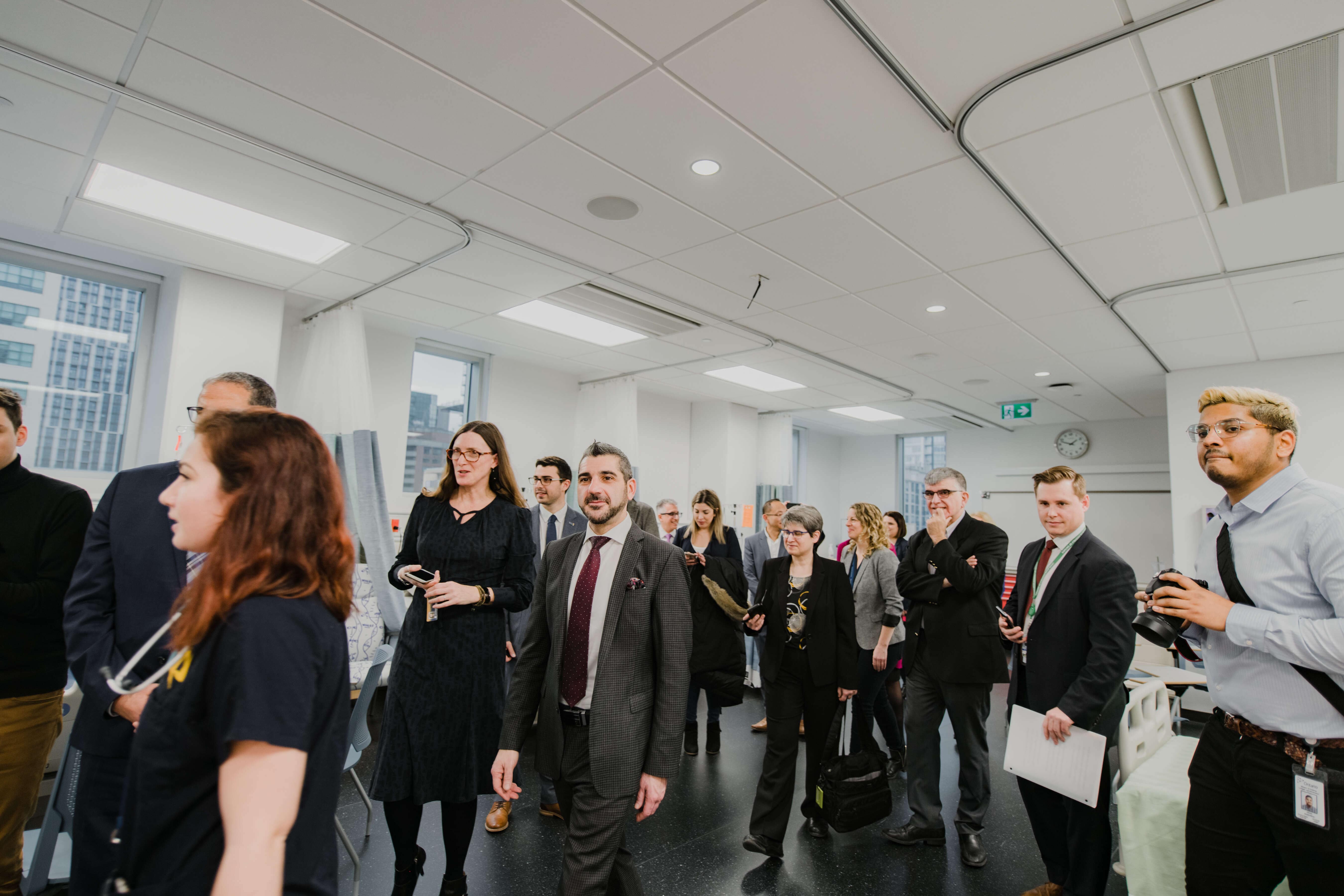 Visitors and university representatives tour a healthcare simulation lab while observing teaching spaces and equipment. The group walks through the facility as staff provide information about the learning environment.