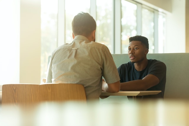 Two men sitting at a table talking