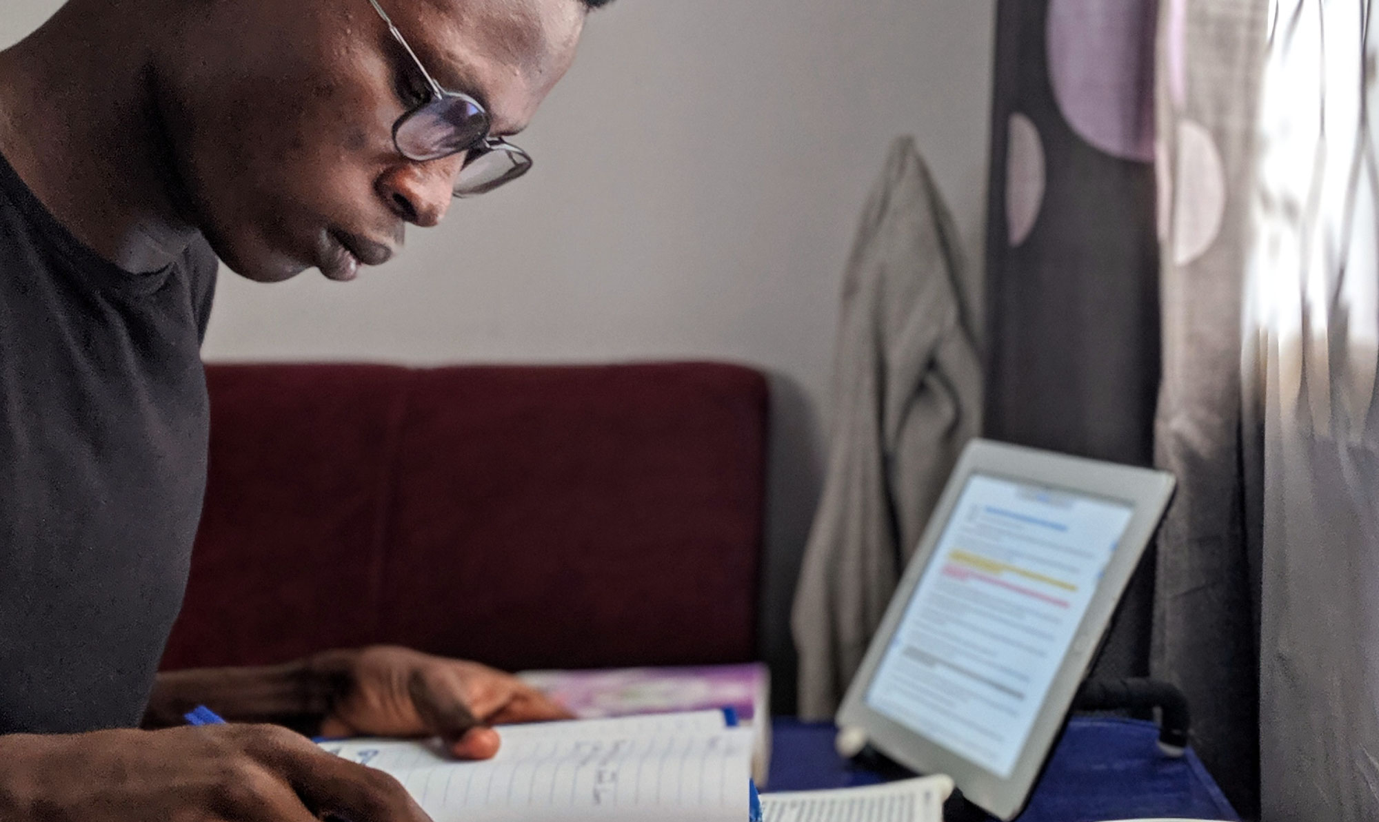 Student reading notes from his notebook, with a laptop off to the side