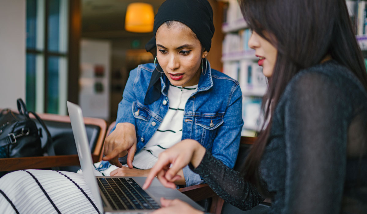 Two female students collaborating on a laptop