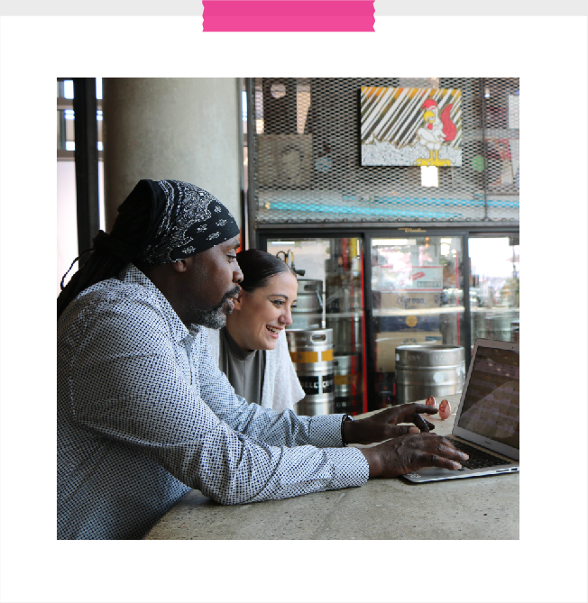 A pair of students happily working together on a project on a laptop