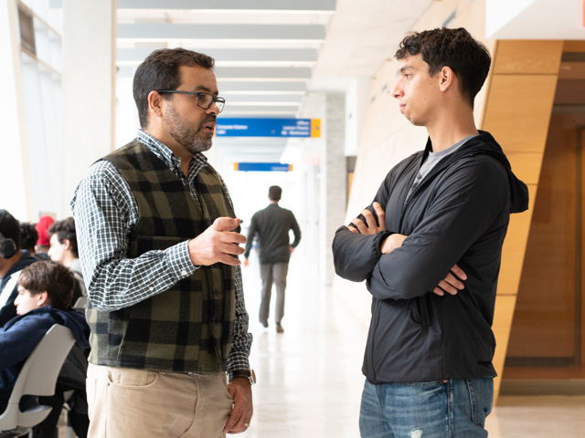 Dr. Marcus Santos chatting with student in hallway.