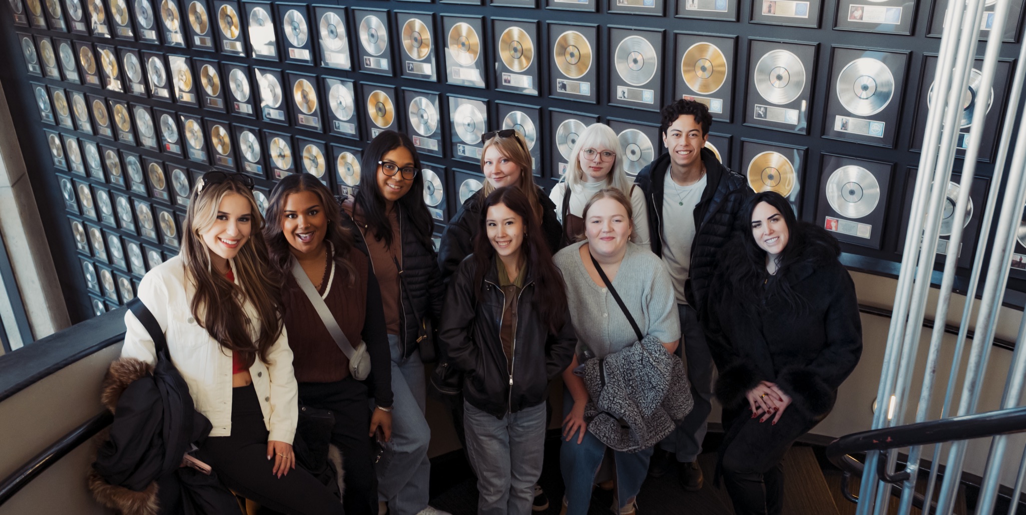  Students pose in front of a wall of gold records, showcasing the program's industry connections. Photo courtesy of Antonio Adams