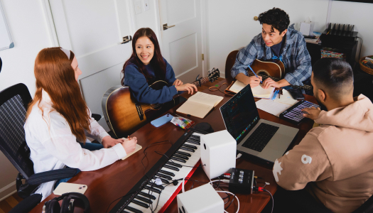 Students working on a table with musical instruments and computers