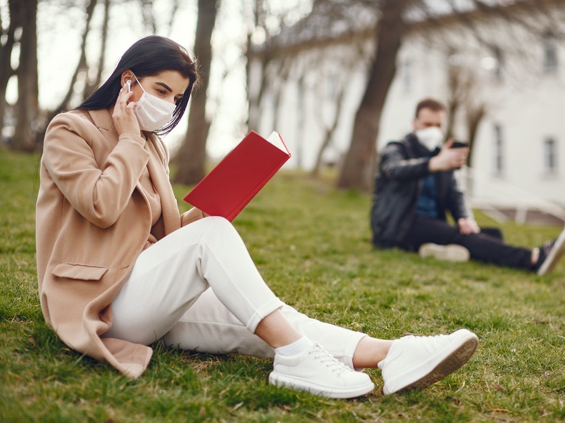 Students studying on the grass wearing masks.