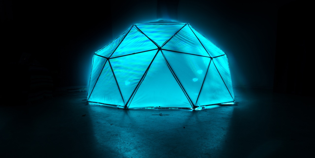 A glowing blue geometric sculpture in a dark room