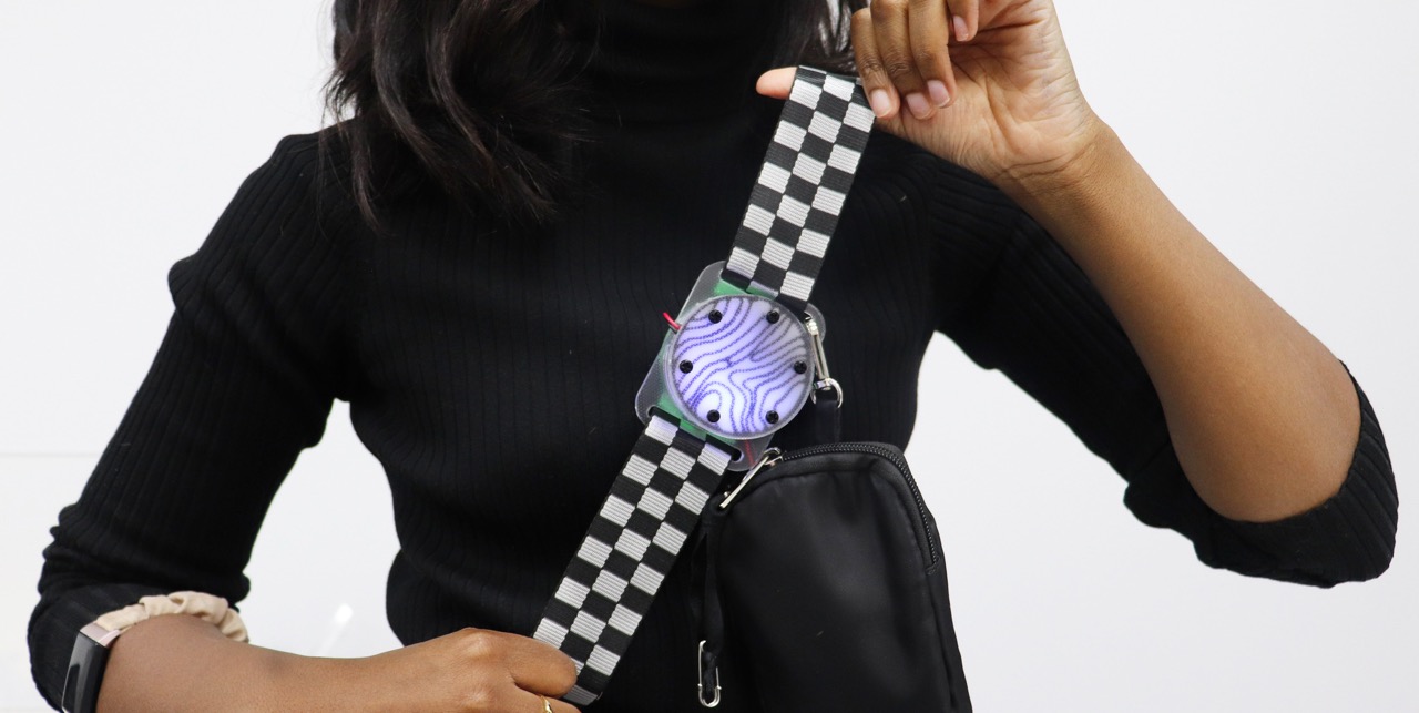 A student models a custom-built, glowing wearable technology device.