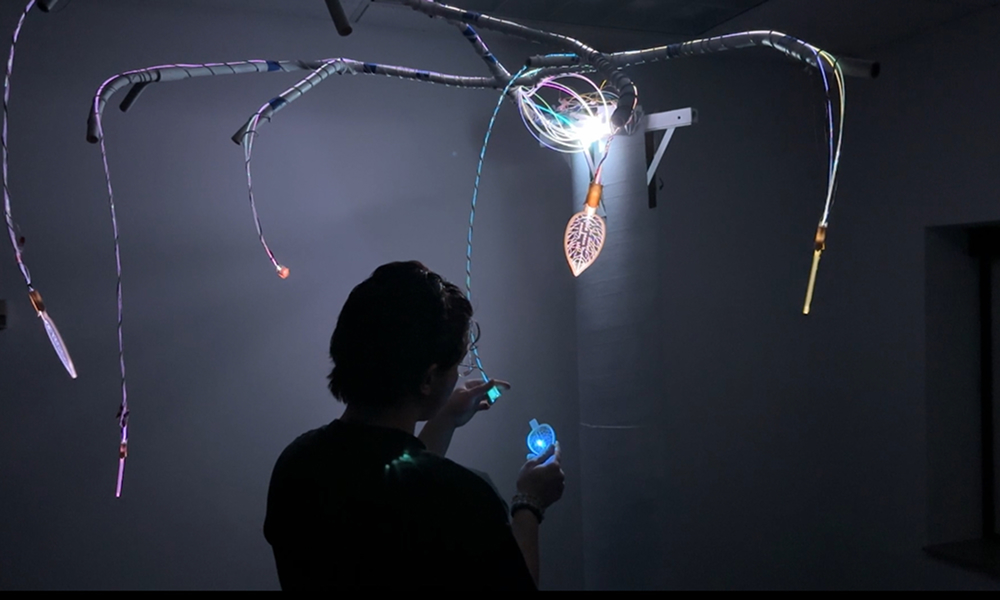 Student working with a light instalation hanging from de ceiling