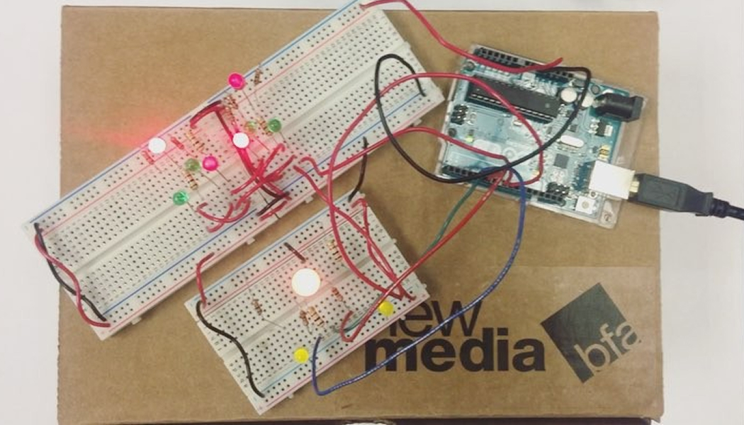 Electronic panels lay ontop of a cardboard box with a print of the New Media logo.