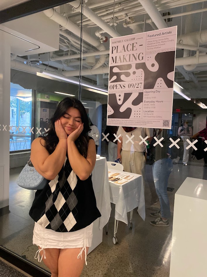 Madeline stands with the poster for the Placemaking exhibition
