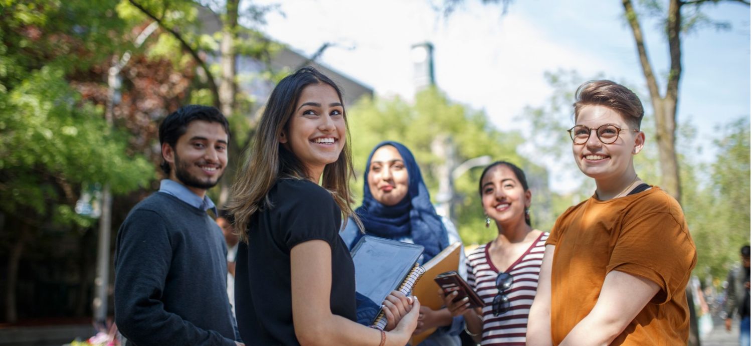 A group of five students smiling on Gould St. on campus.