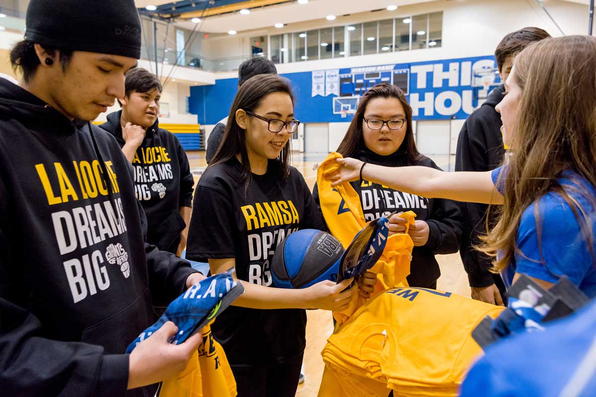 Rams player handing out Rams shirts to students