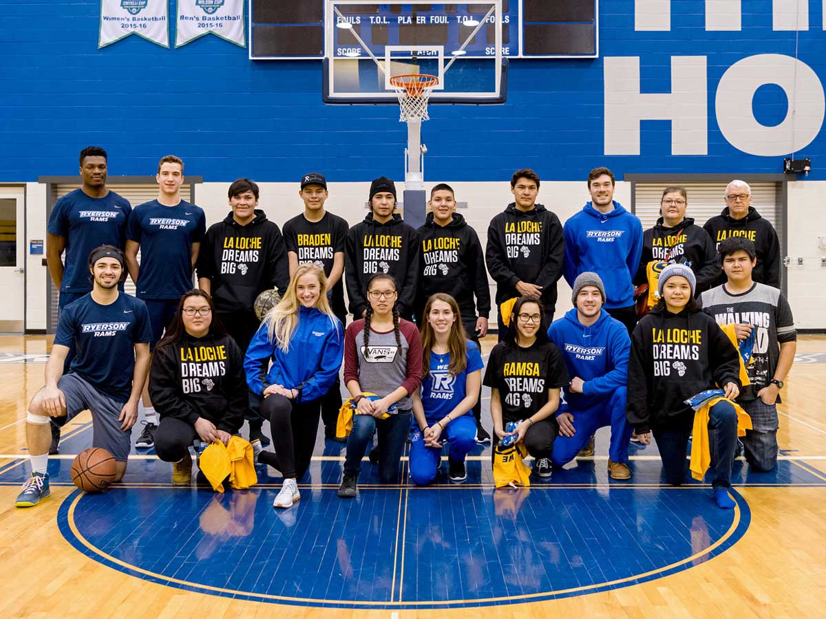 Team photo of Rams players and La Loche students