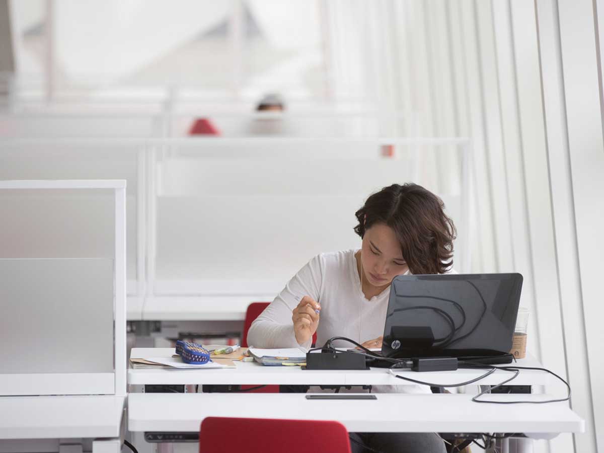 Female student studying at desk with laptop