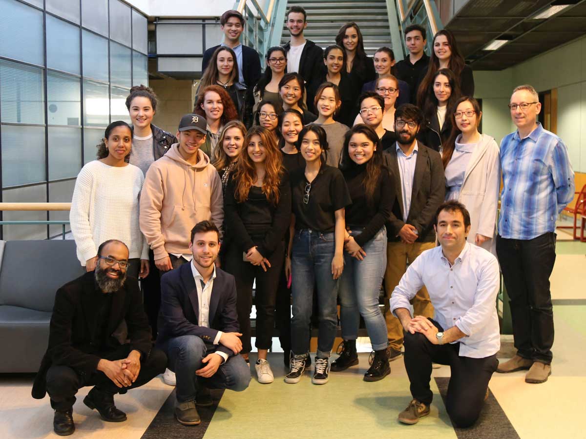 Supercourse students and professors pose in front of stairs