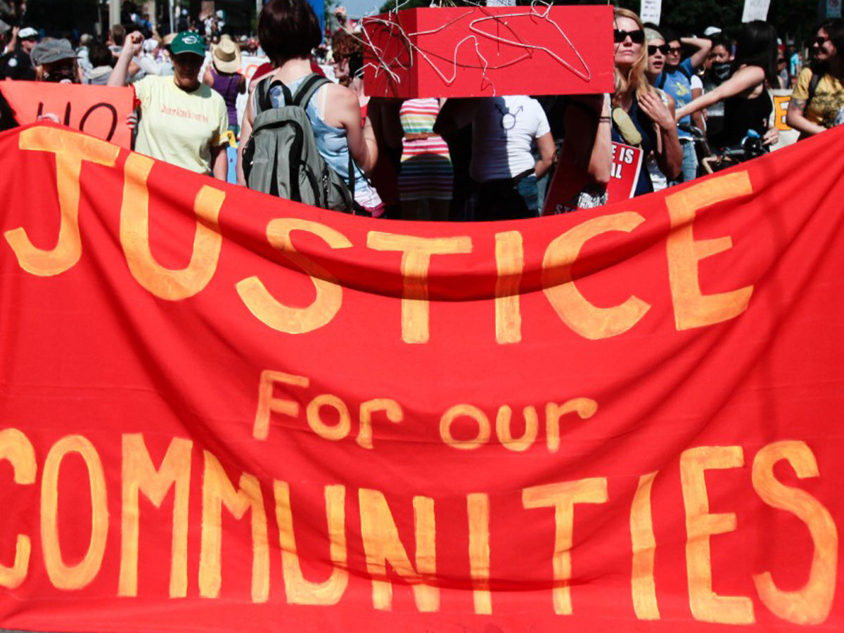 Protesters carrying sign that says ‘justice for our communities’