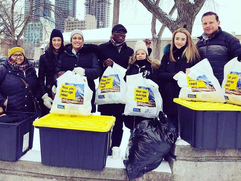 People wearing black winter clothes holding bags of used clothing