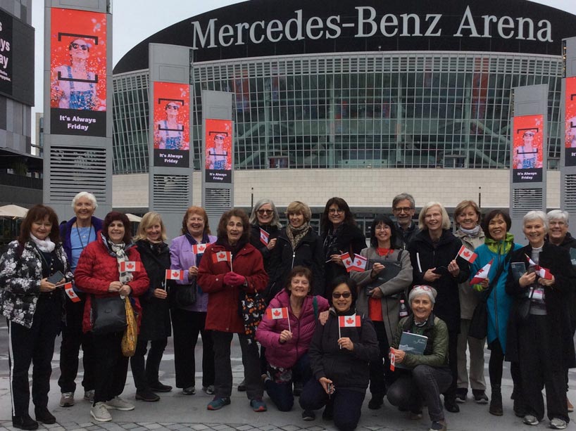 Singers from the Oakham House Choir in Berlin holding small Canadian flags