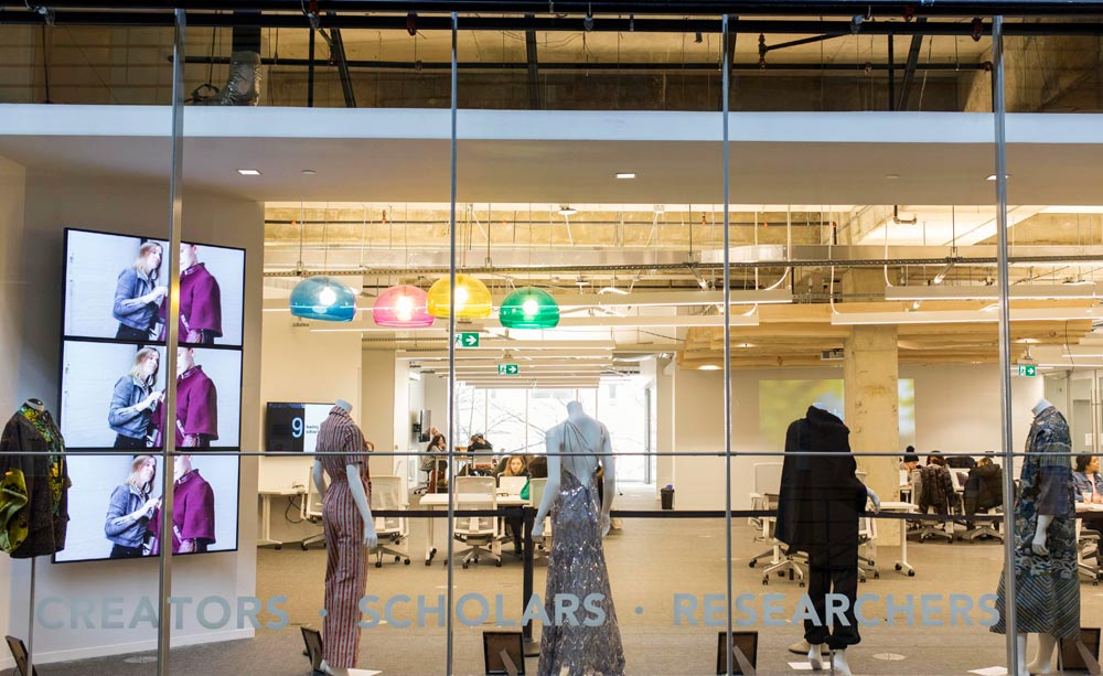 Five dressed mannequins in front of a window 