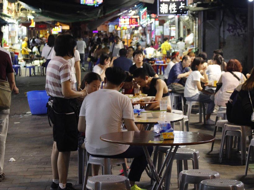 People in Hong Kong sitting at tables, eating and talking in a street market