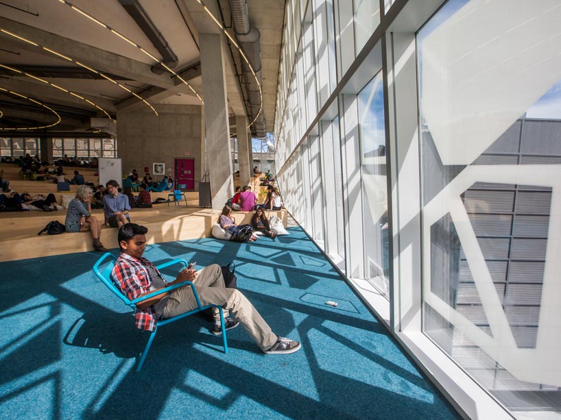 Students sitting in chairs, facing a window on the top floor of the Student Learning Centre