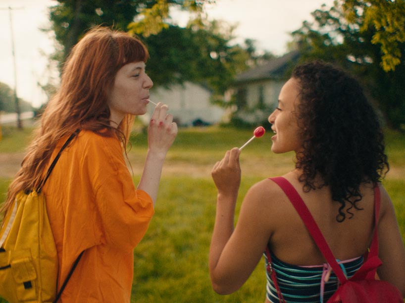 Two women facing eachother holding lollipops