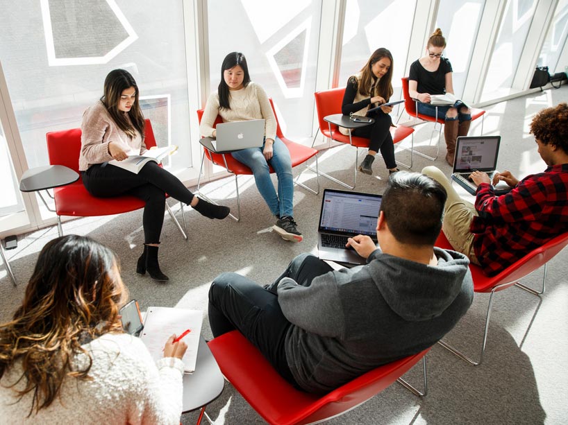 Students sitting in chairs, on their laptops