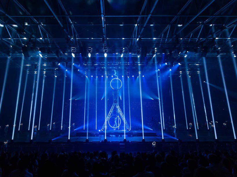 Two figures balancing on stage rings under blue lighting at a Cirque du Soleil event