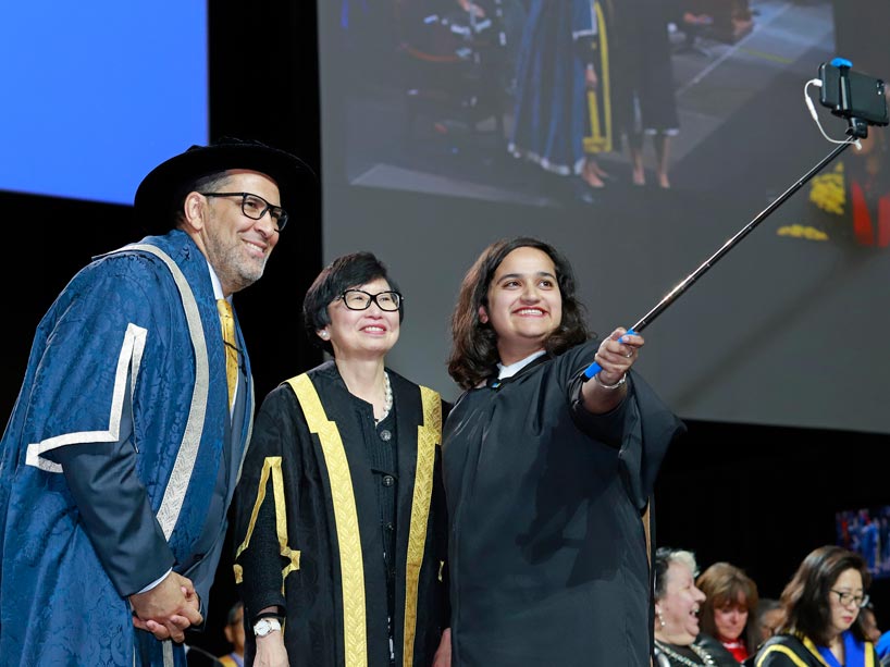 From left: Mohamed Lachemi, Janice Fukakusa and a student using a selfie stick to take a photo on stage