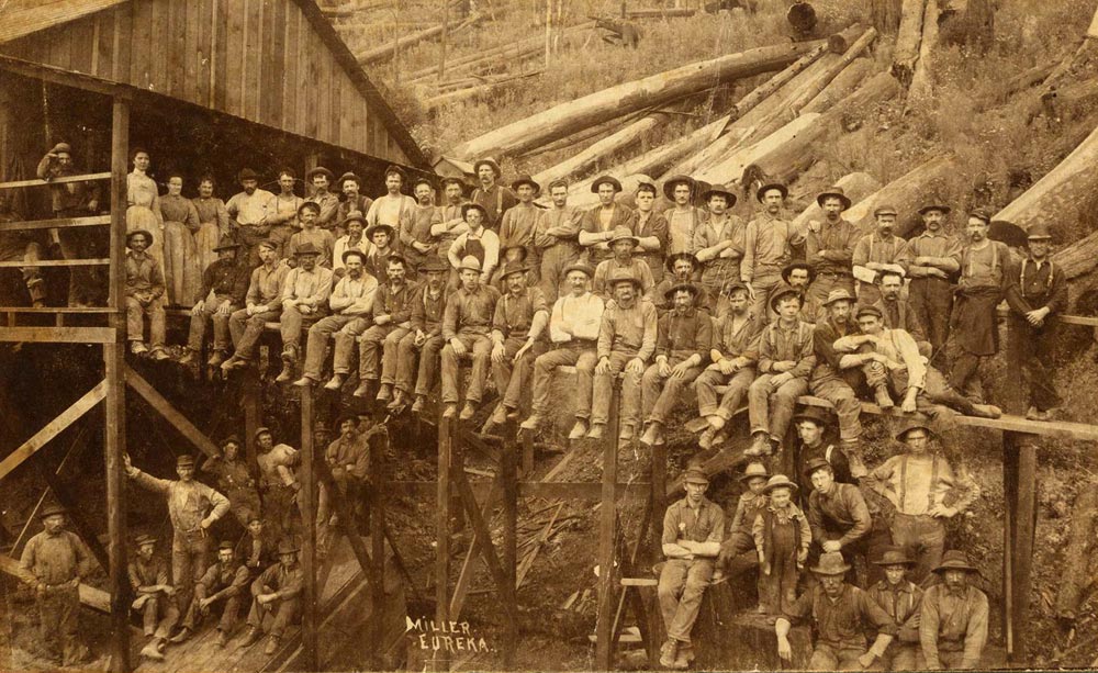 More than 60 workers sit or stand on, or under, a wooden structure about 1883 to pose for a group photo at the Eureka Woolen Mill