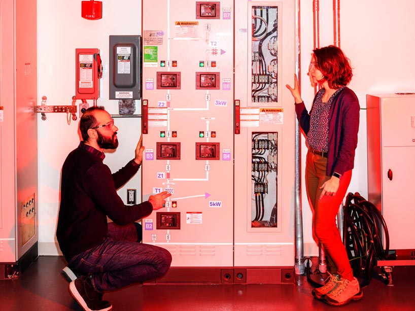 Two students standing in front of electrical equipment