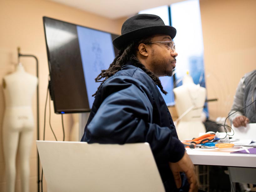 Quentin VerCetty sits at a table with textiles