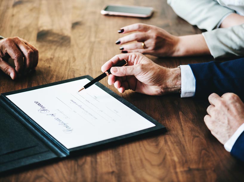 A man and a woman sit at a table to sign a certificate of divorce