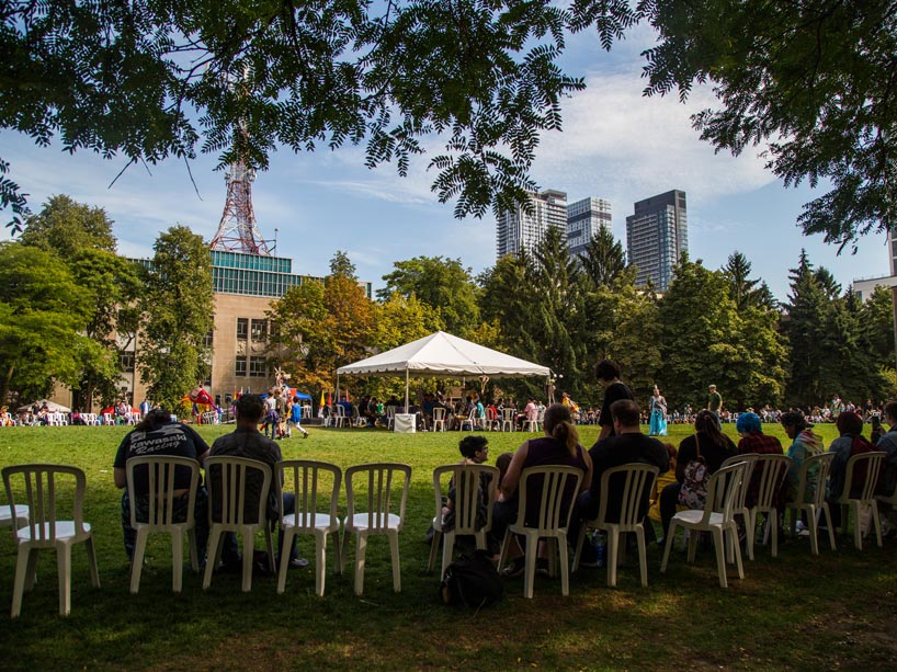 People sitting in chairs around the quad watching dancers in the middle