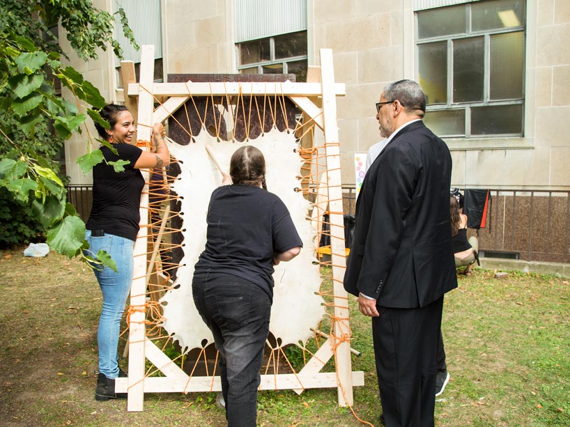 From left: Two women stretch out an animal hide while President Mohamed Lachemi speaks to them