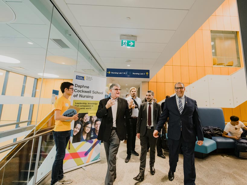 University officials lead Minister of Colleges and Universities through a bright, airy corridor of the building