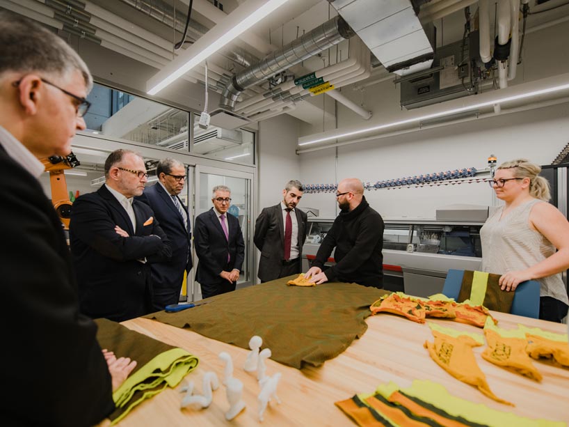 Officials are shown different textiles placed over a large wood table within the Creative Technology Lab