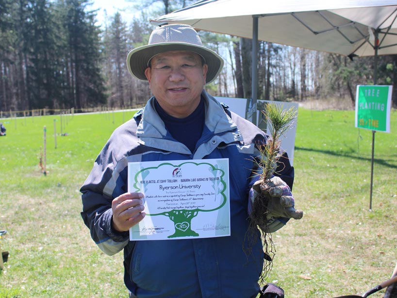 Rodney Yip holds a seedling and certificate explaining the number of trees planted in Ryerson’s name