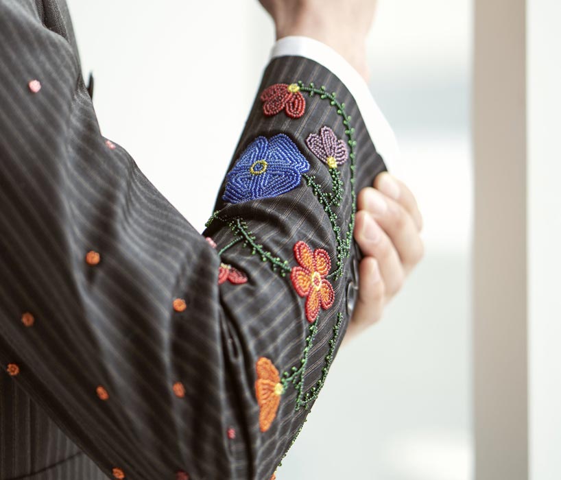 A jacket sleeve displaying purple, red and orange flowers crafted with beads.
