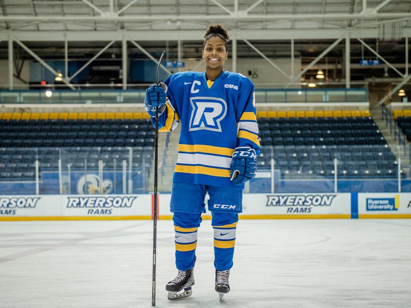 Man hockey player in sports uniform and skates standing on ice arena with  stick in his