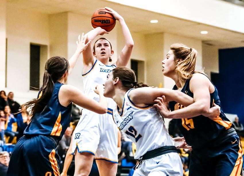 A female basketball player about to shoot a jump shot with three other players around her