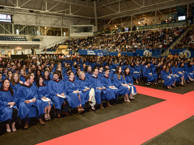People wear blue gowns, seated at convocation