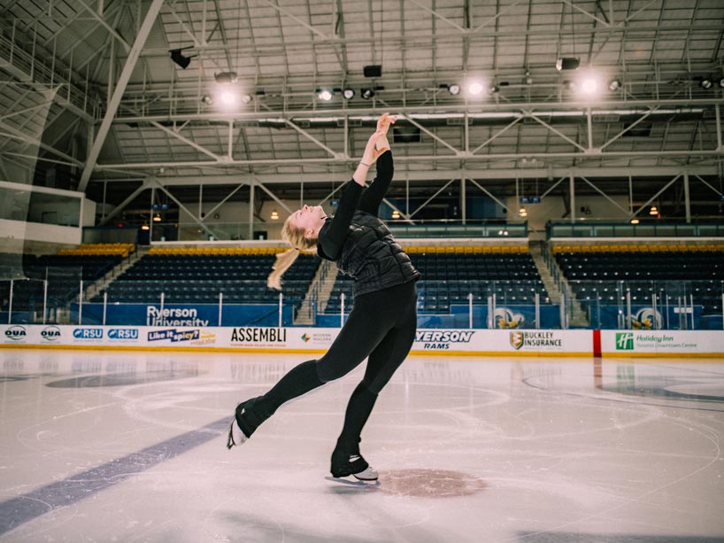 Young female ice skater performs a spin on the rink