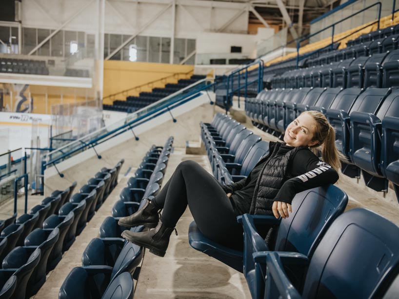 Young woman sits in the stands in a relaxed posture