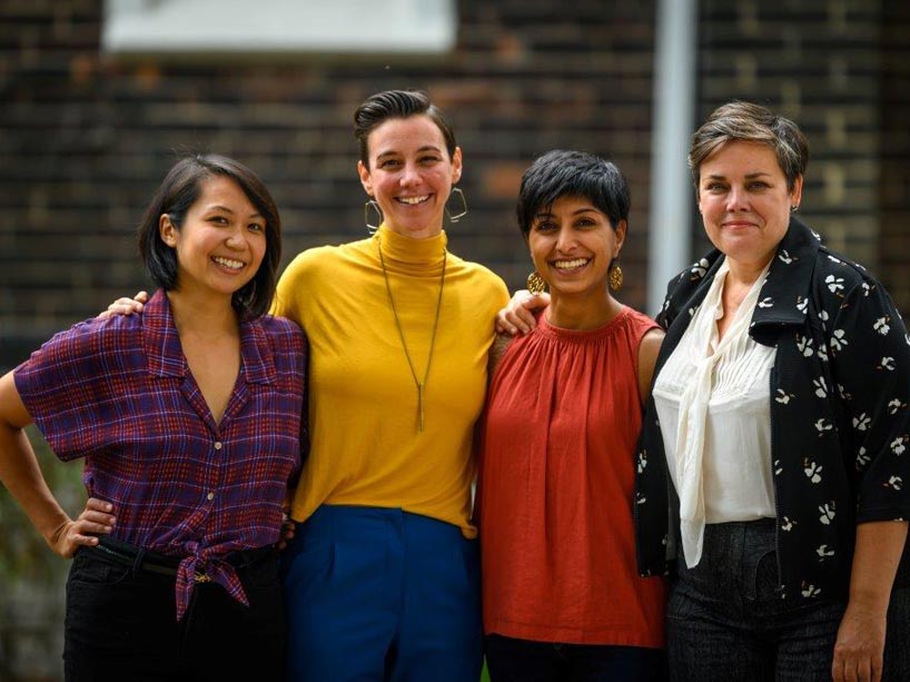 Four people stand together smiling