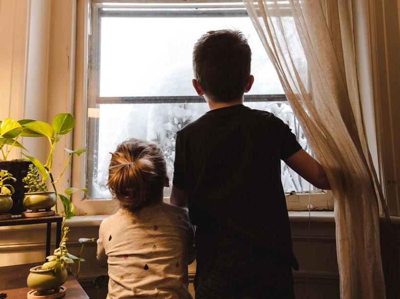 Boy and girl standing near window looking outside