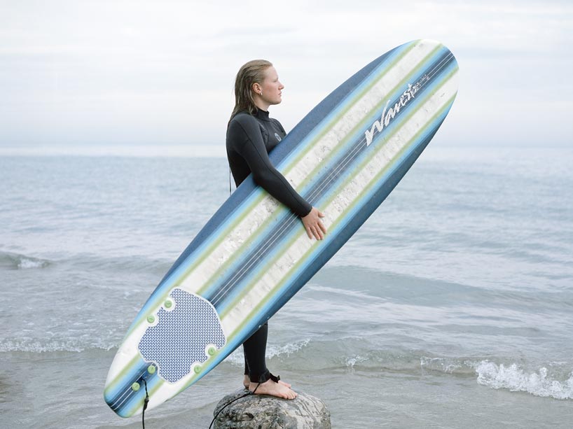 A surfer holding their board on the beach