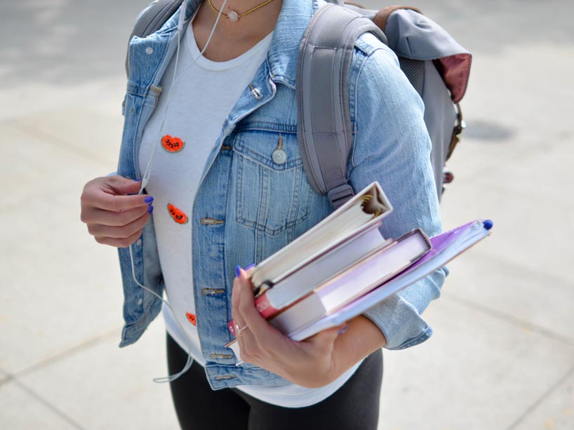 woman wearing blue denim jacket holding book